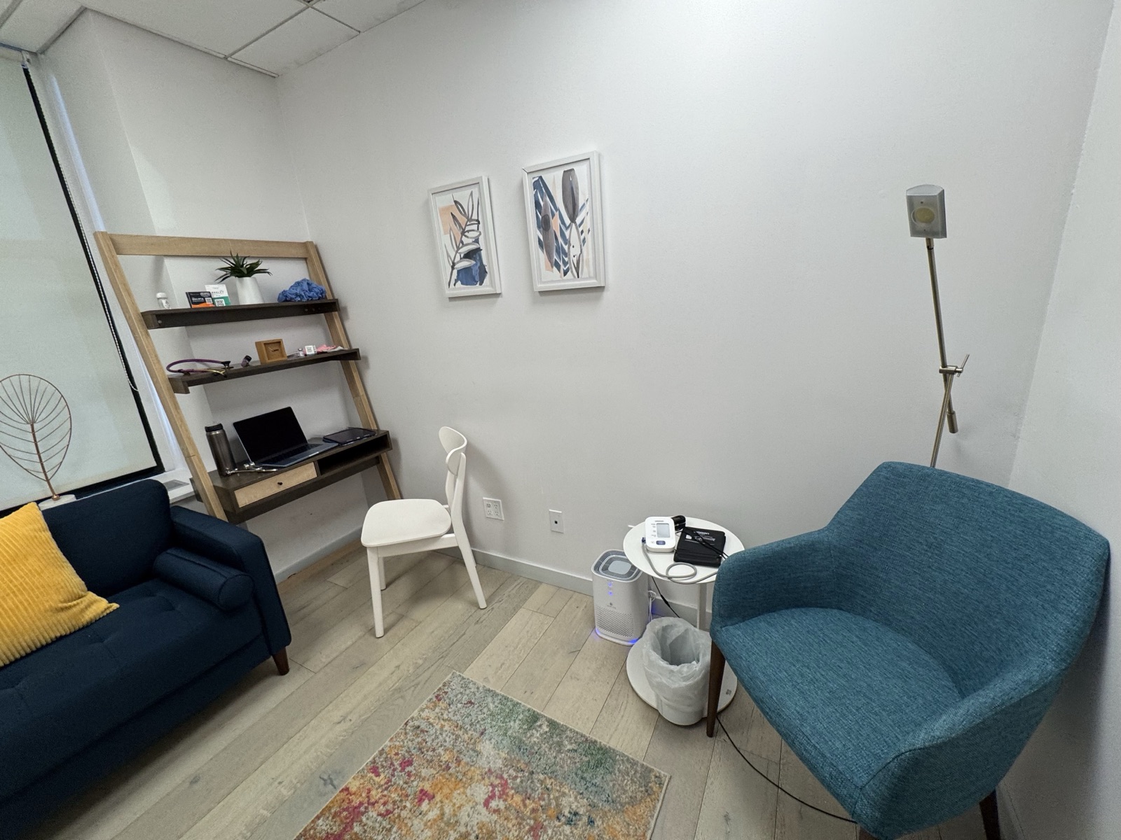 Consultation room at Robin Warner Neurology with desk, ladder shelf, and blood-pressure equipment beside the seating area